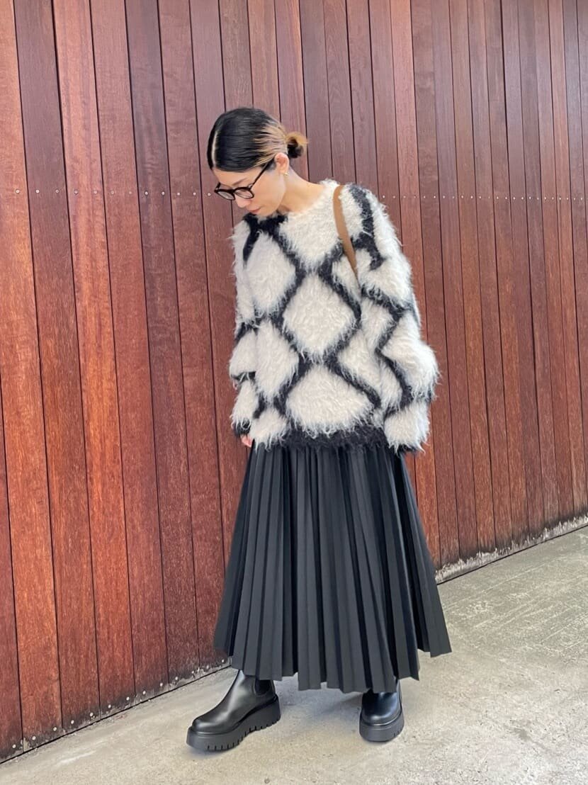 ニットとプリーツスカートを着た女性