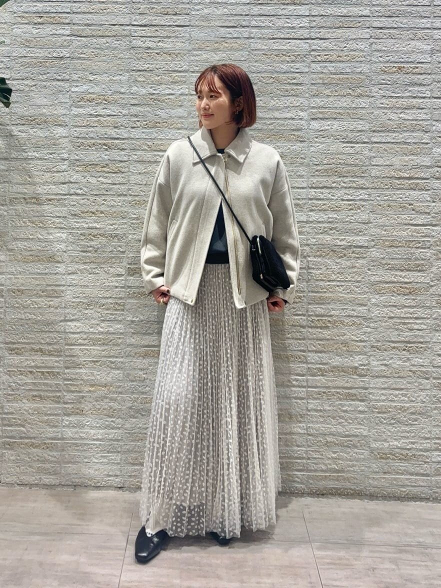 ミドルコートとプリーツスカートを着た女性
