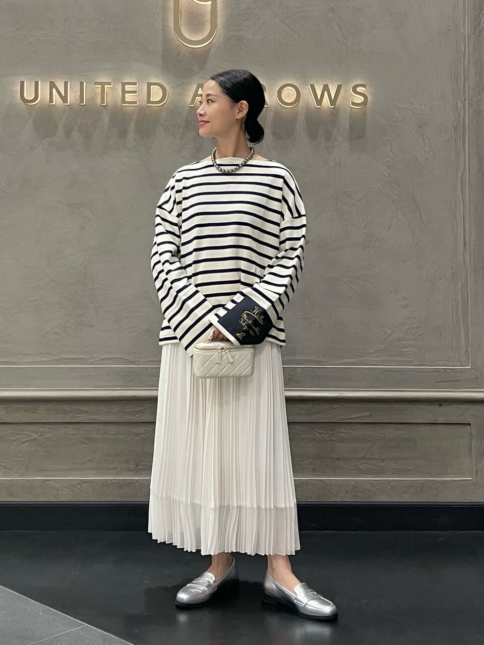 ボーダーカットソーとプリーツスカートを着た女性