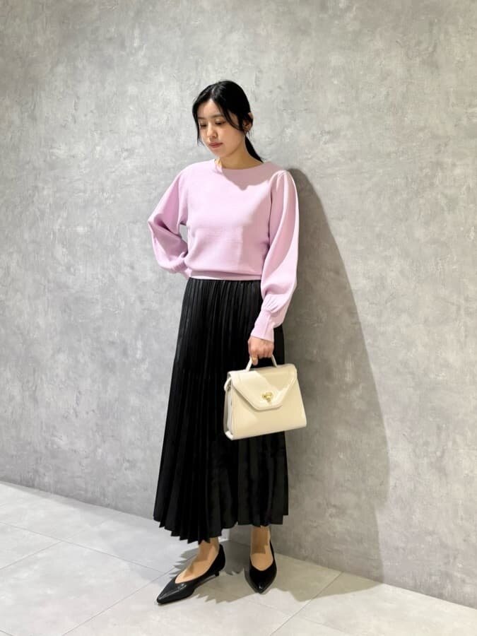 ニットとプリーツスカートを着た女性