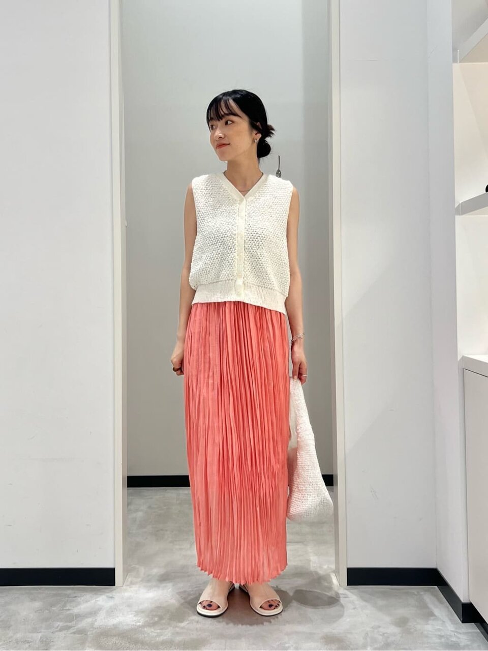 ニットベストとプリーツスカートを着た女性