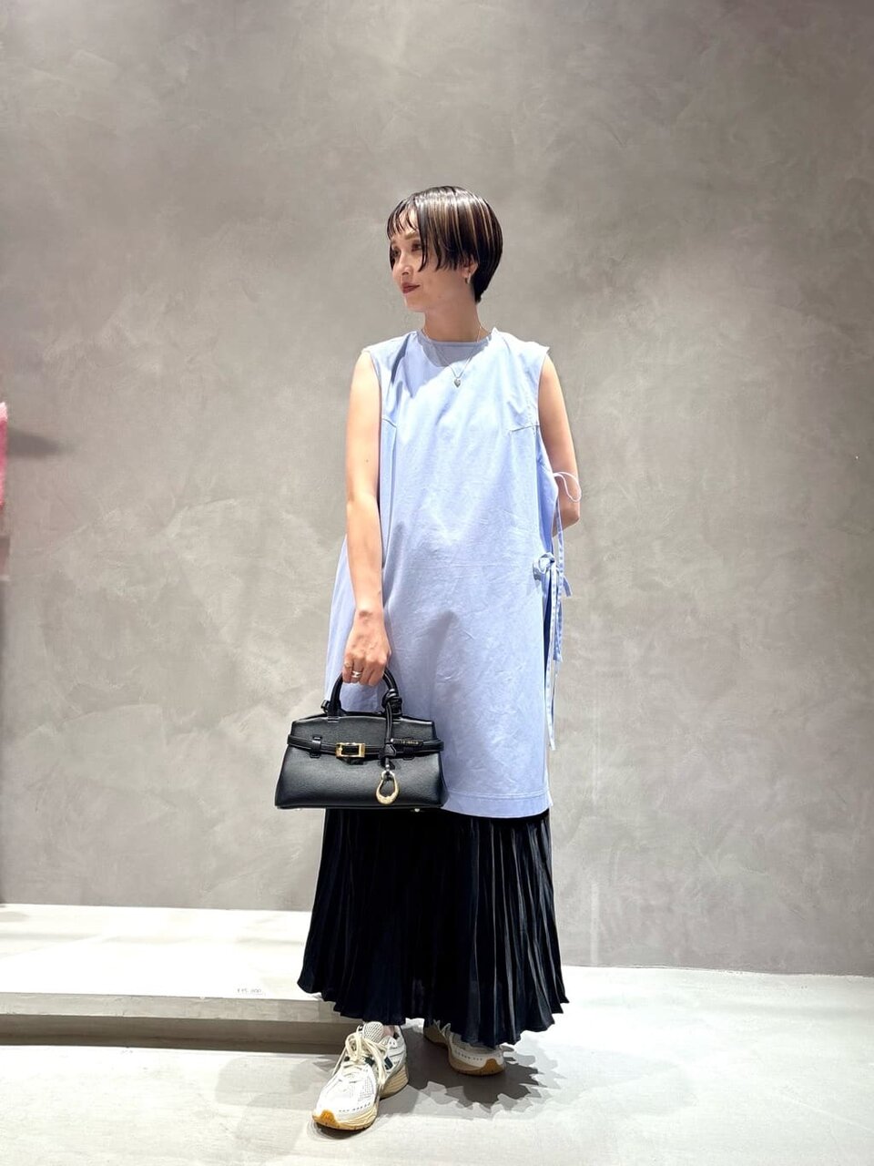 ノースリーブチュニックとプリーツスカートを着た女性