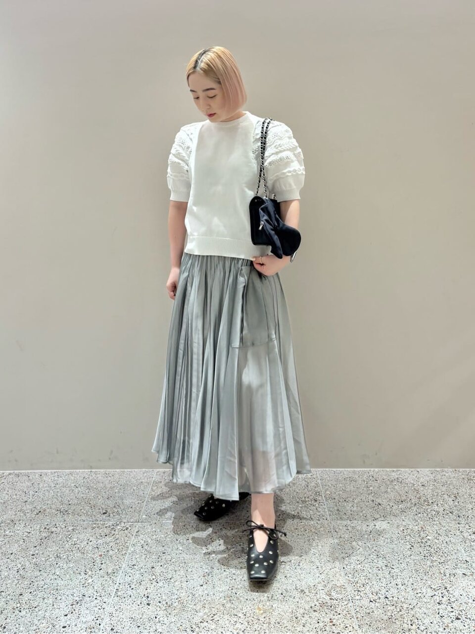 半袖ニットとプリーツスカートを着た女性