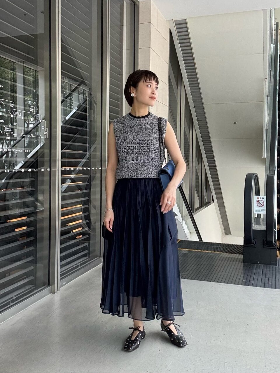 ニットベストとプリーツスカートを着た女性