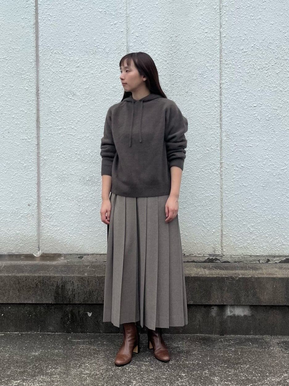 フーディーとプリーツスカートを着た女性