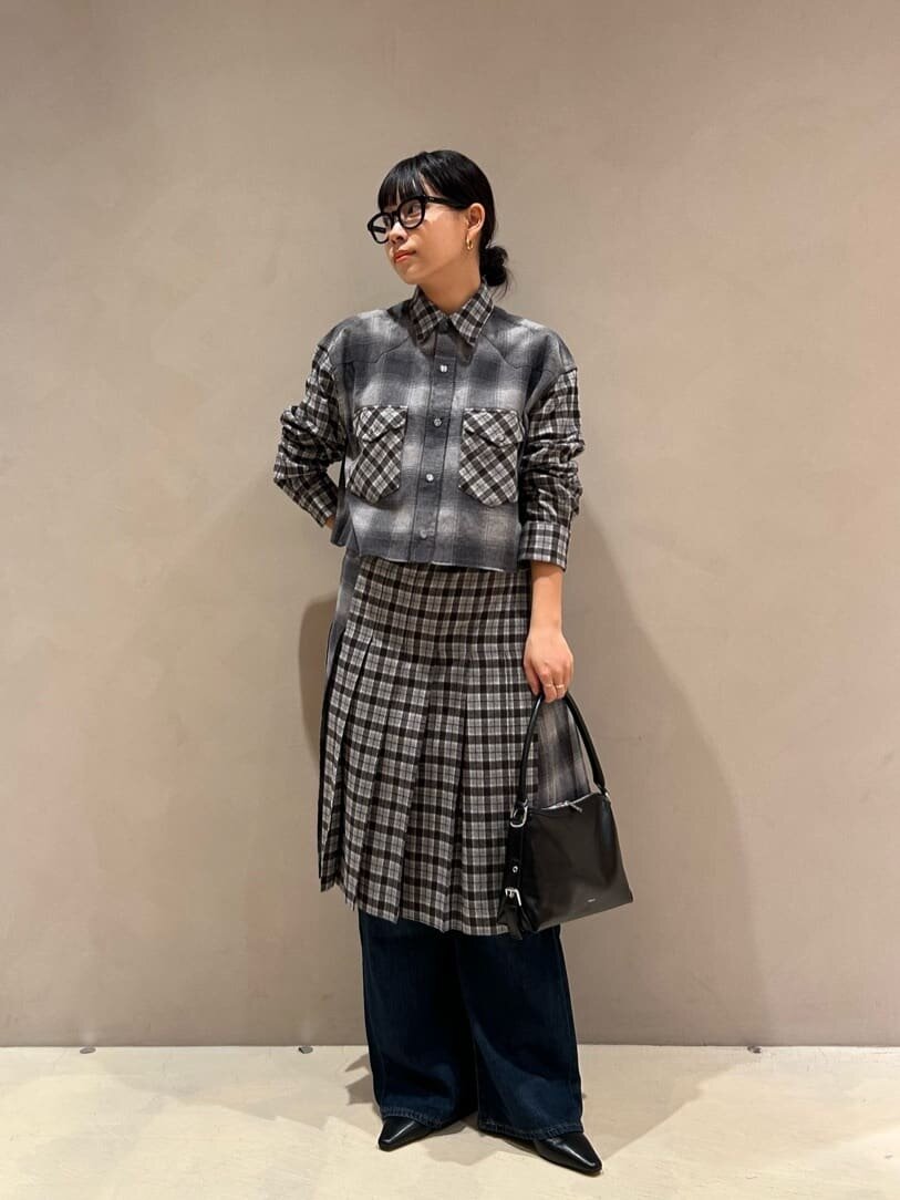 チェックシャツとプリーツスカートを着た女性