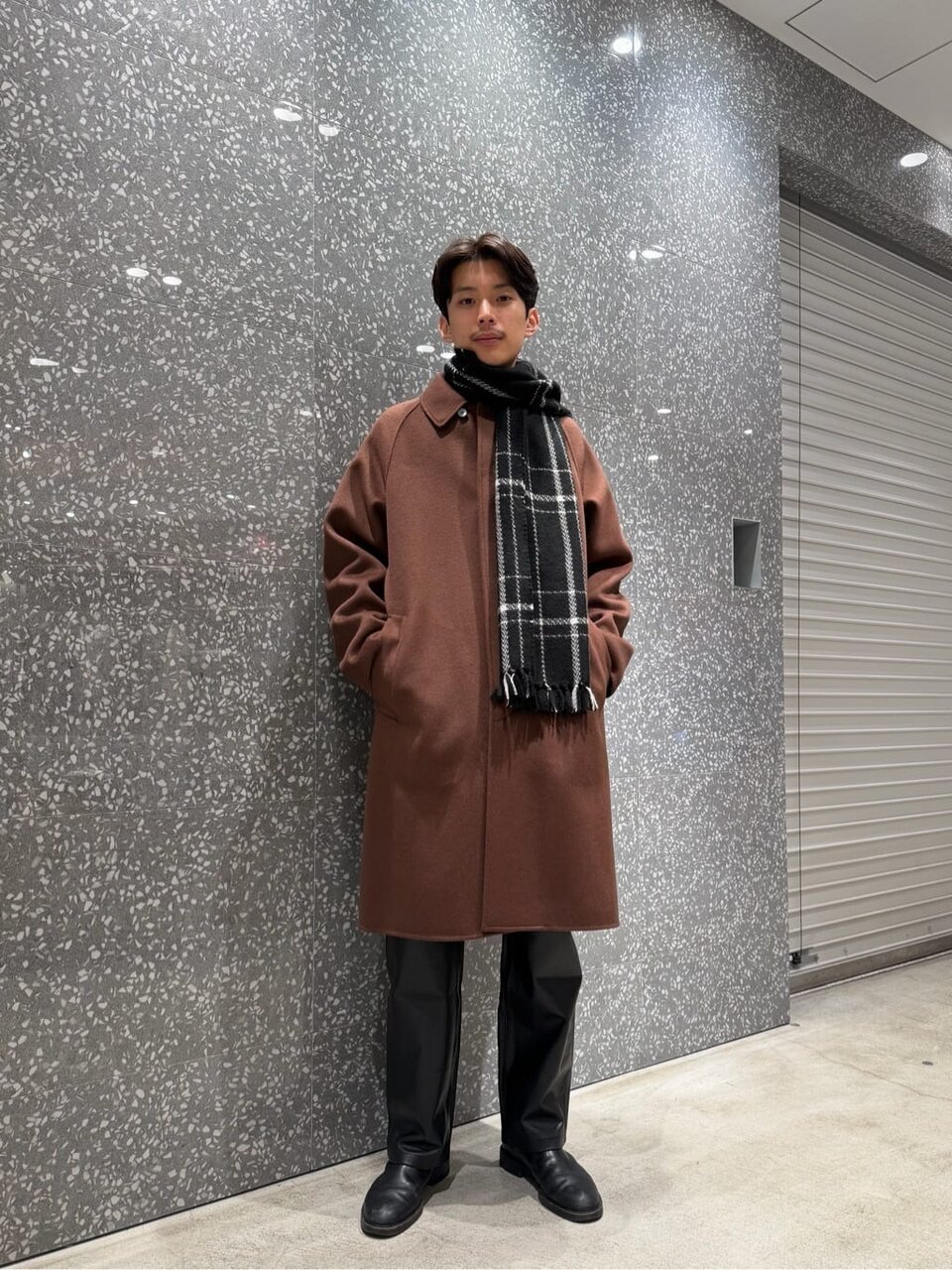 ステンカラーコートとレザーパンツを着た男性