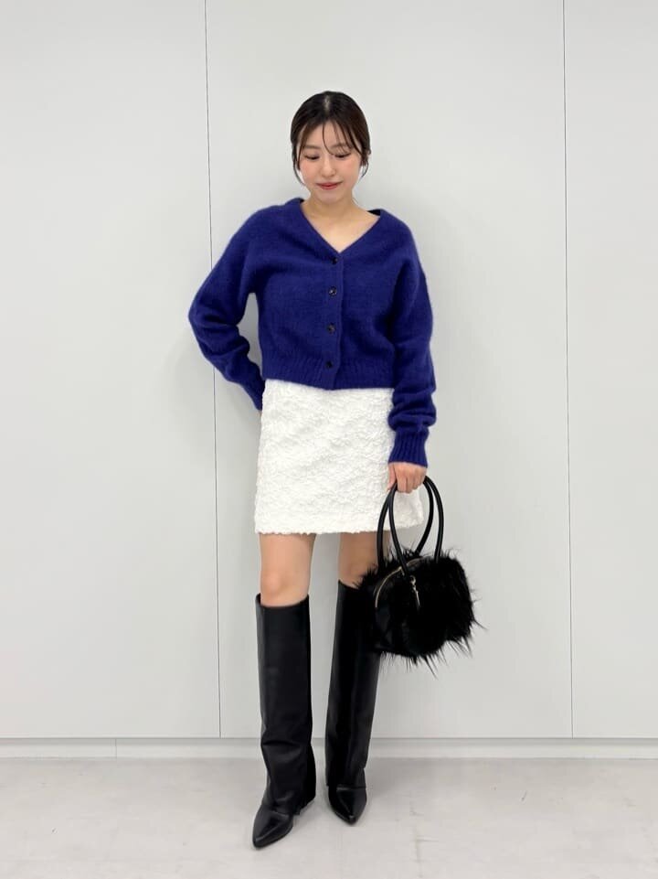 紫のカーディガンと白のミニスカートを着た女性