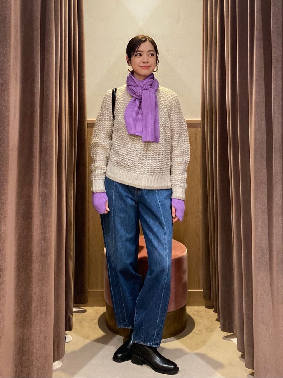 紫のマフラーとベージュのニットを着た女性