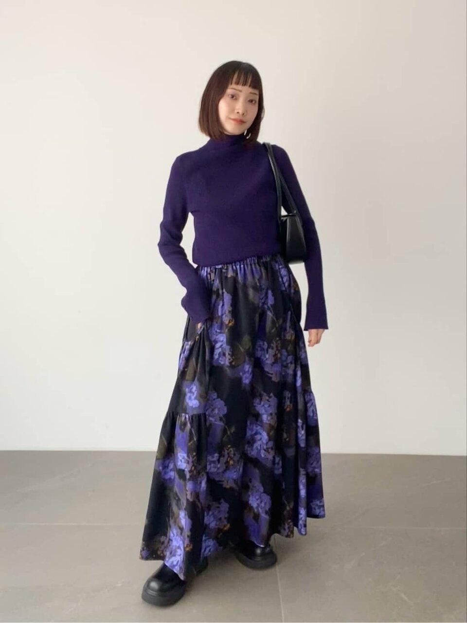 ネイビーのニットと紫の花柄スカートを着た女性