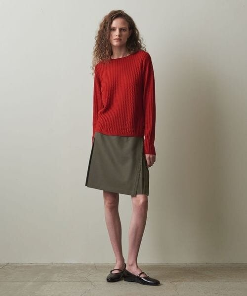 オリーブグリーンのスカートと赤のニットを着た女性
