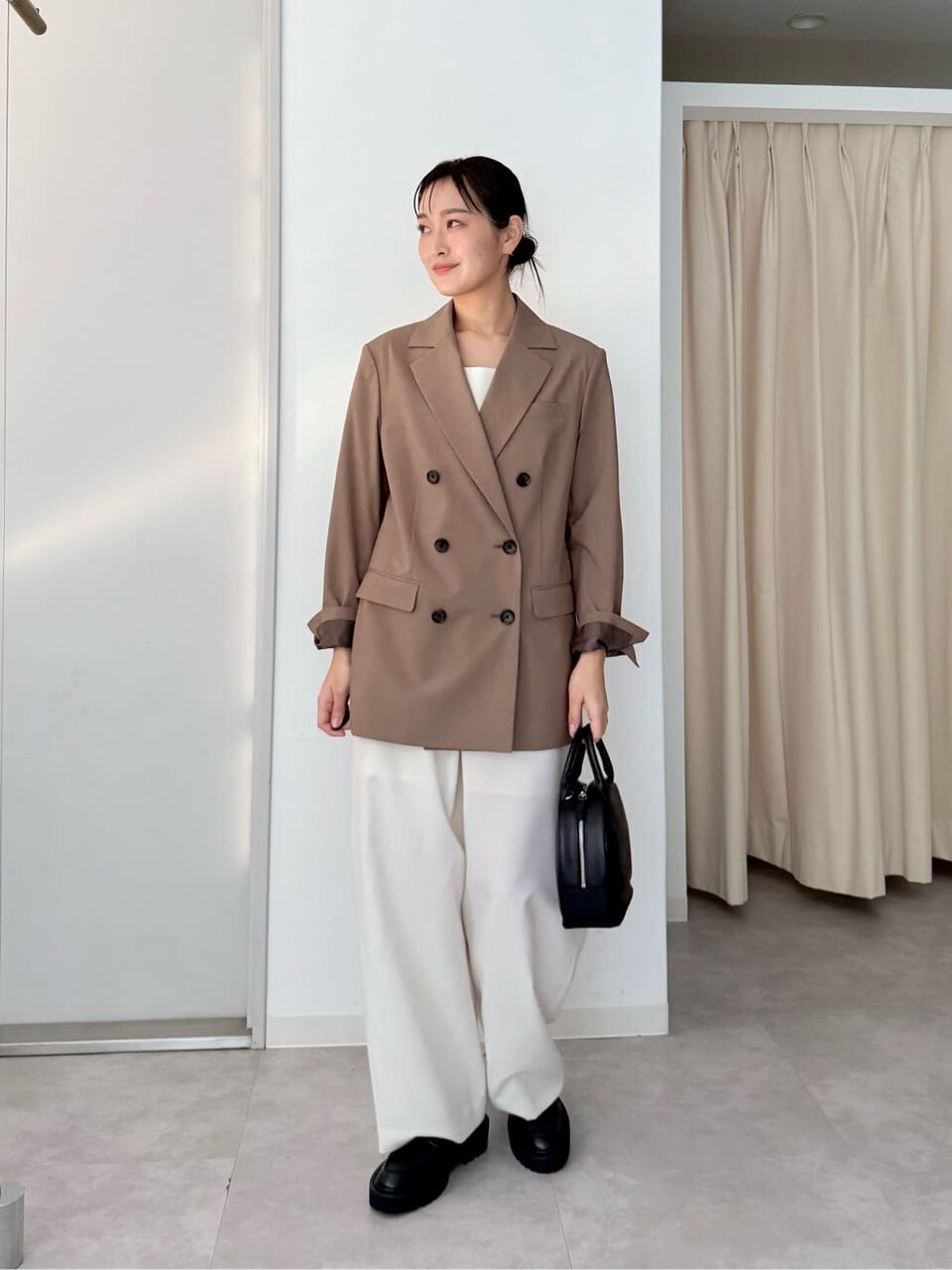 ブラウンのジャケットと白いパンツを着た女性