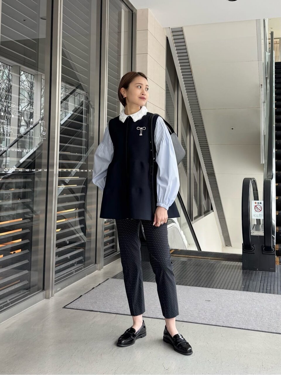 ペプラムシルエットのベストとテーパードパンツを着た女性