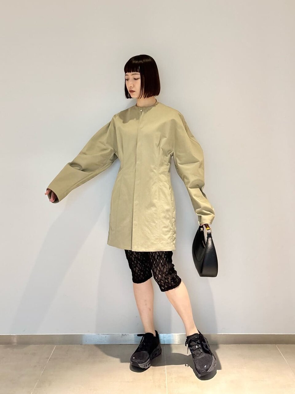 ベージュのハーフコートに黒いスニーカーを着た女性