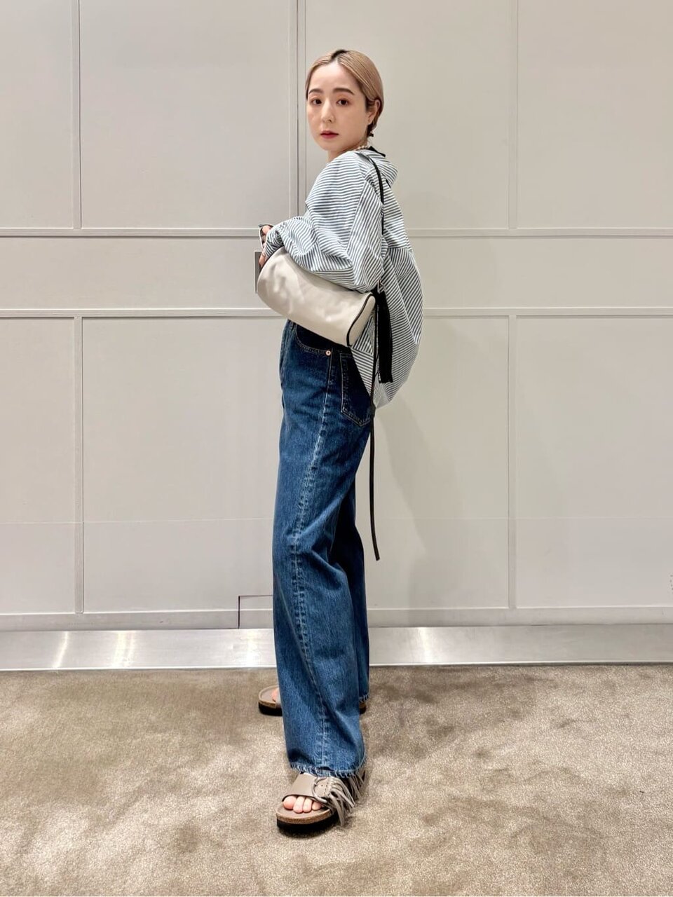 デニムにフリンジつきのサンダルをあわせた女性