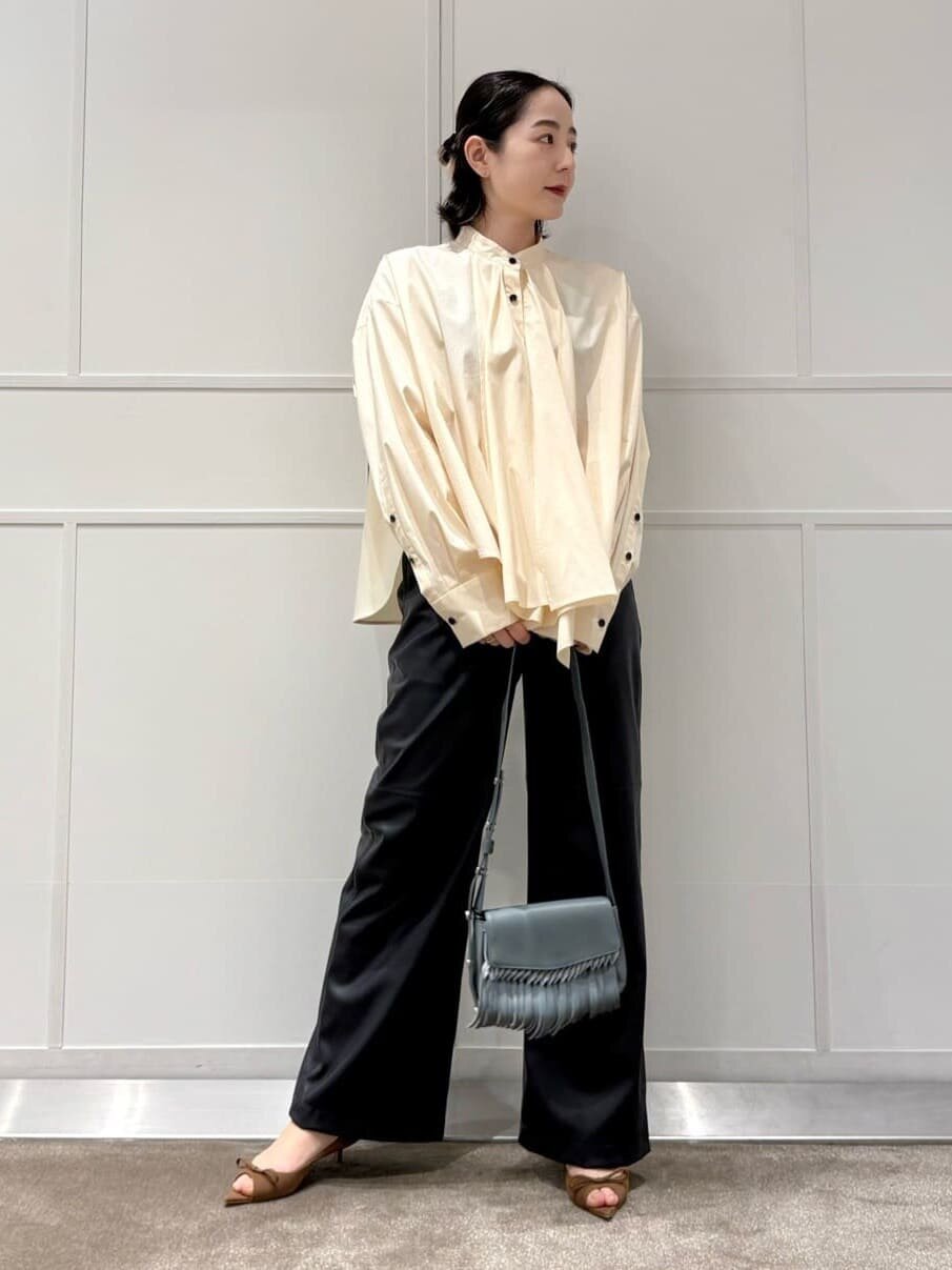 白いブラウスにレザーライクなパンツを着た女性