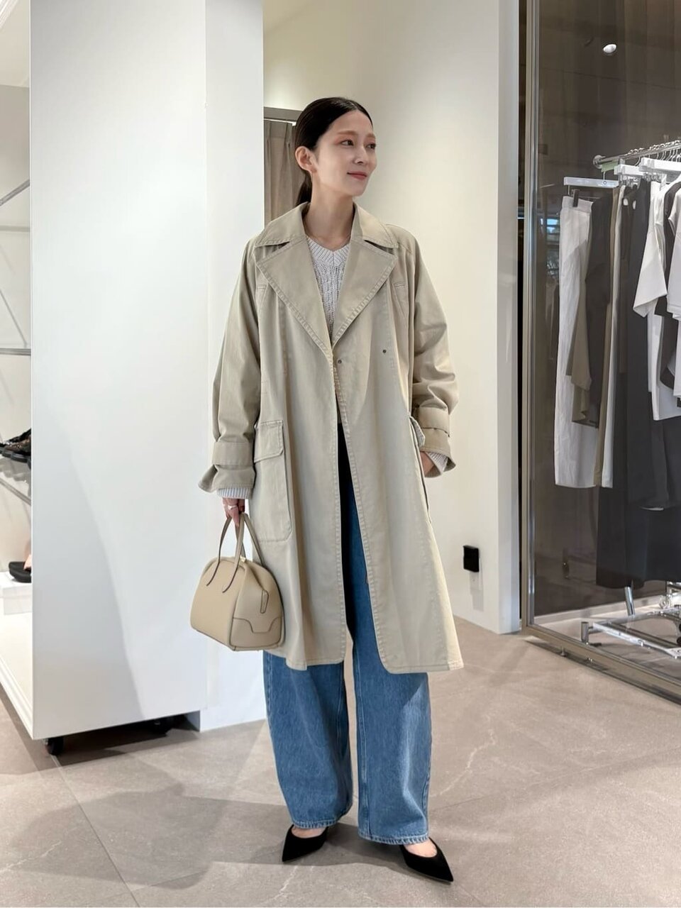 トレンチコートにデニムパンツをあわせた女性