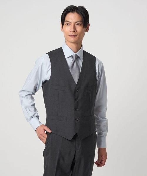 スリーピーススーツのジャケットを脱いだ男性