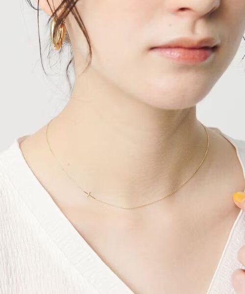 シンプルなクロスネックレスをつけた女性
