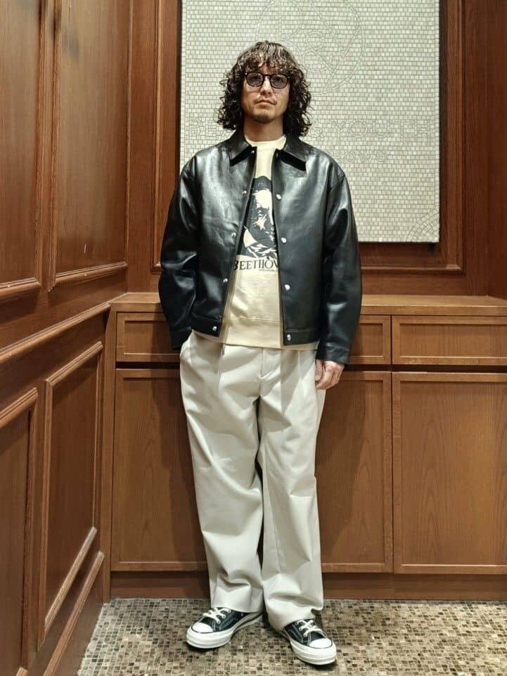 黒のレザージャケットにナチュラルカラーのパンツをあわせた男性