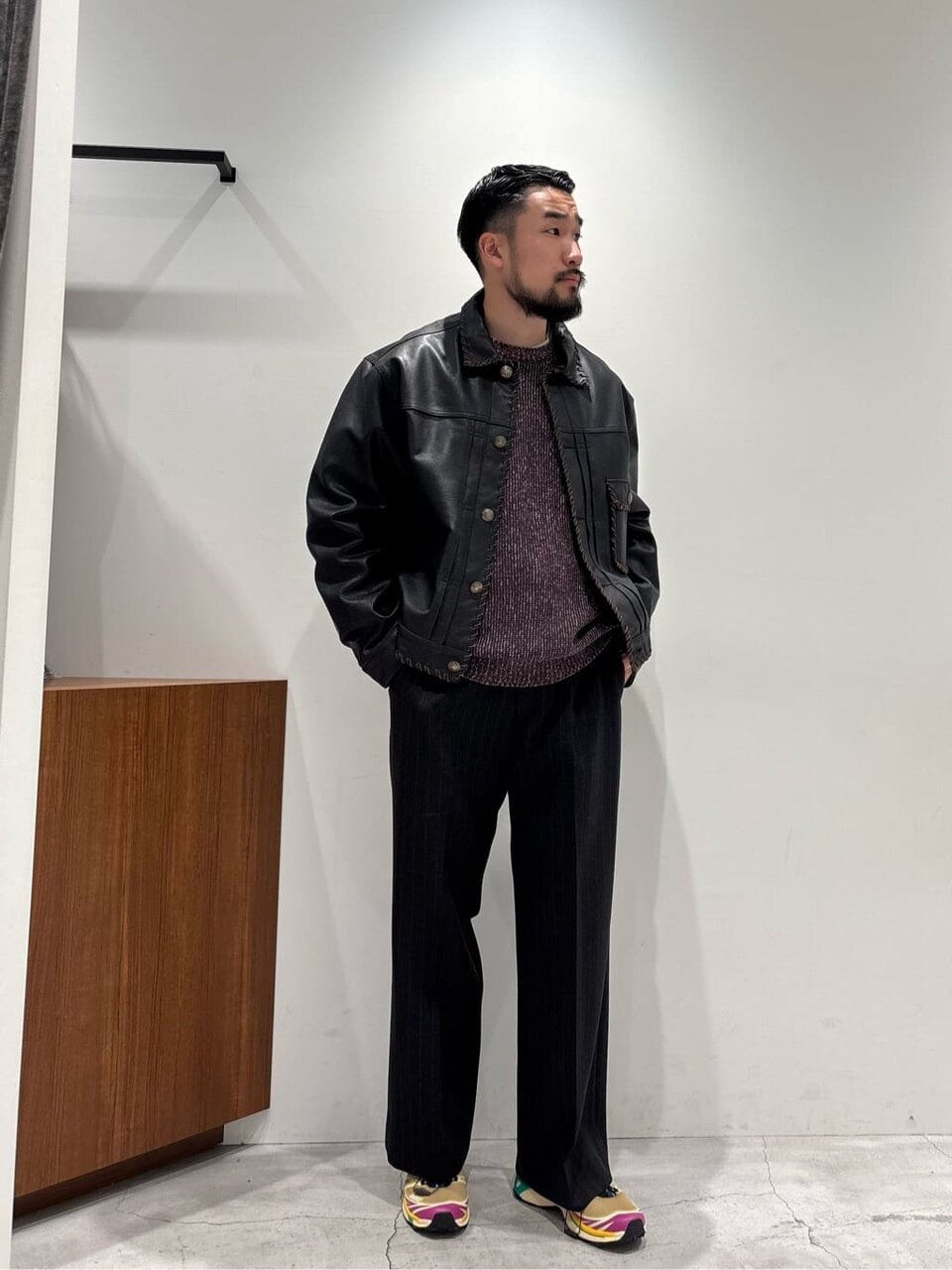 黒のレザージャケットにダークグレーのインナーをあわせた男性