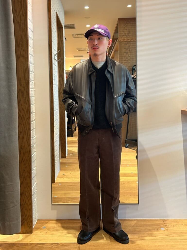 ダークブラウンのレザージャケットとパンツをあわせた男性