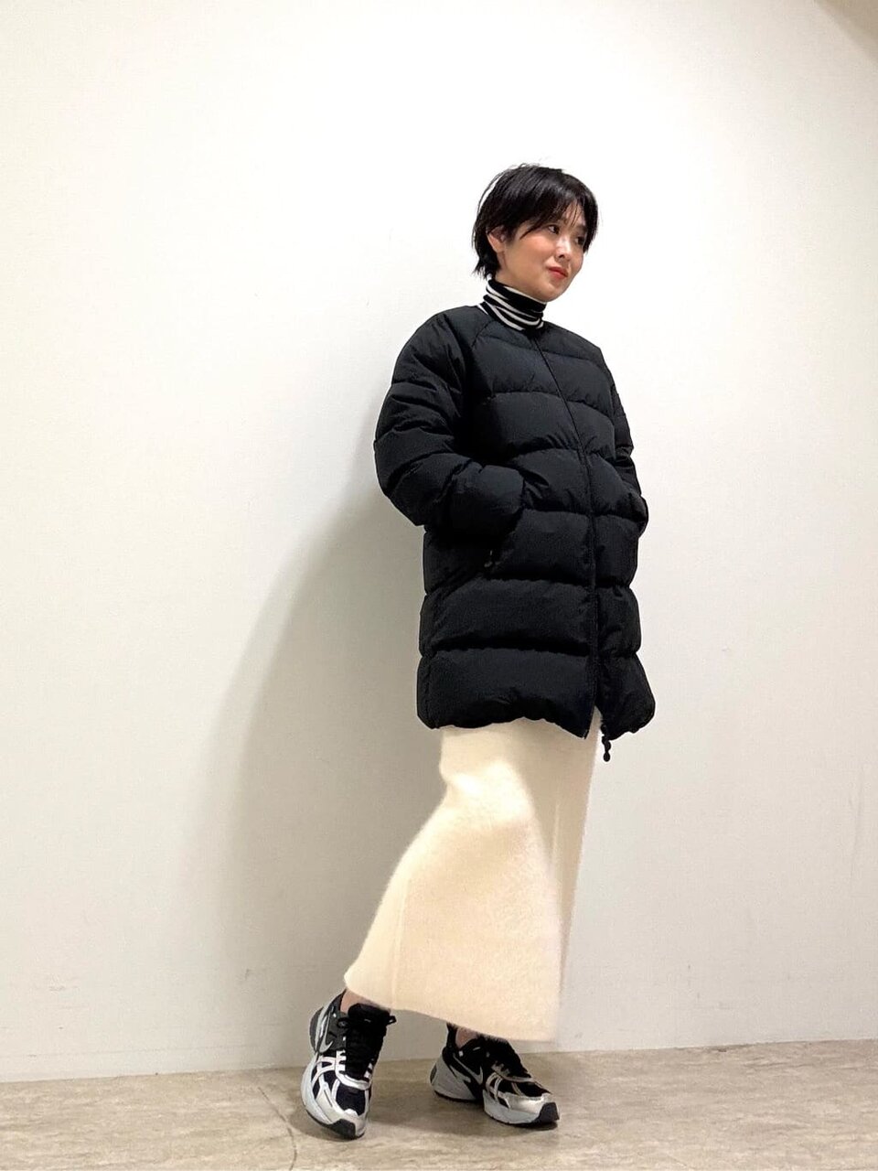 ダウンジャケットと白いニットタイトスカートを着た女性