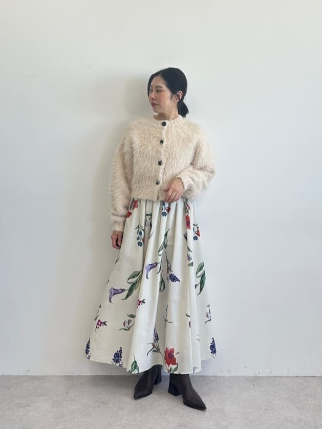 シャギーカーディガンとフラワープリントスカートを着た女性