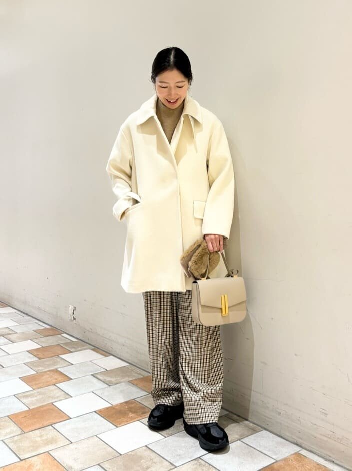 スタンドカラーのミドルコートとチェックパンツを着た女性