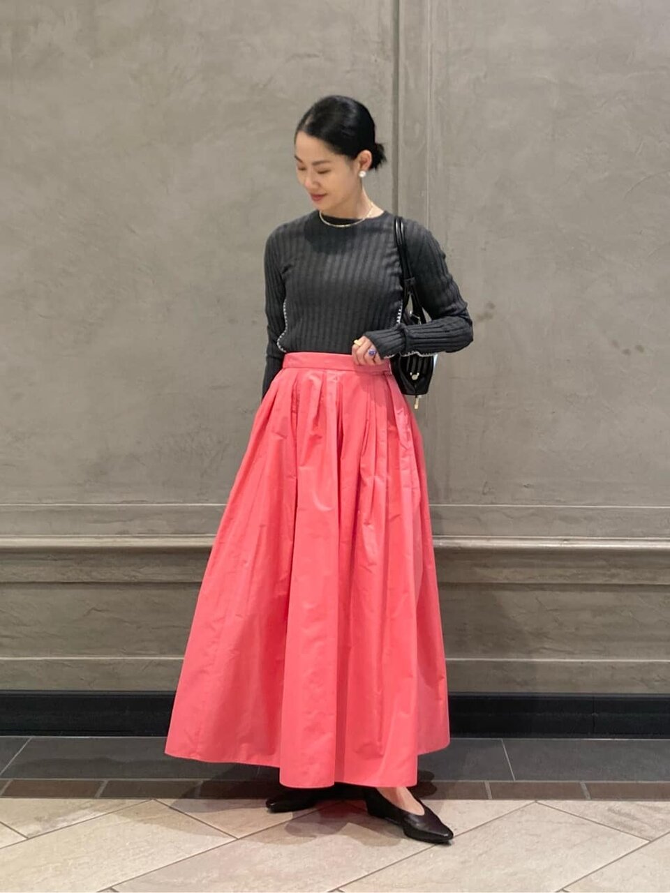グレーのニットにピンクのスカートを着た女性