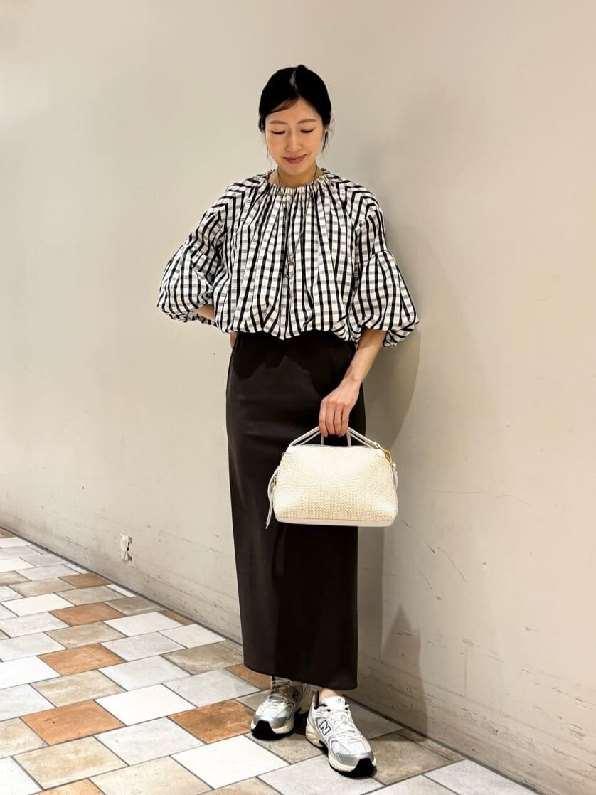 ギンガムチェックのブラウスに黒いタイトスカートを着た女性