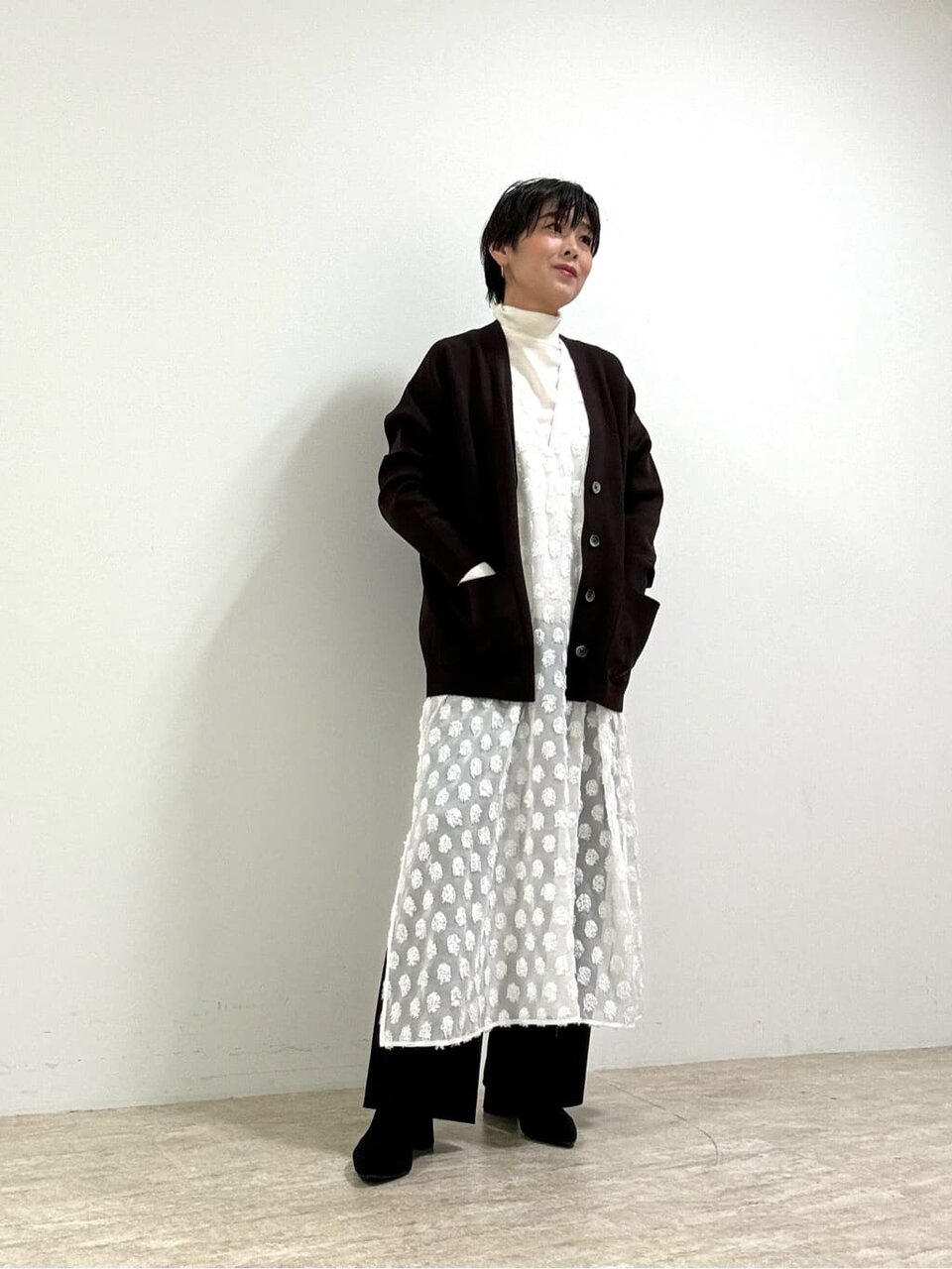 白いワンピースに黒のニットカーディガンを羽織った女性