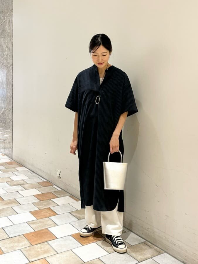 シャツワンピースと白いパンツを着た女性