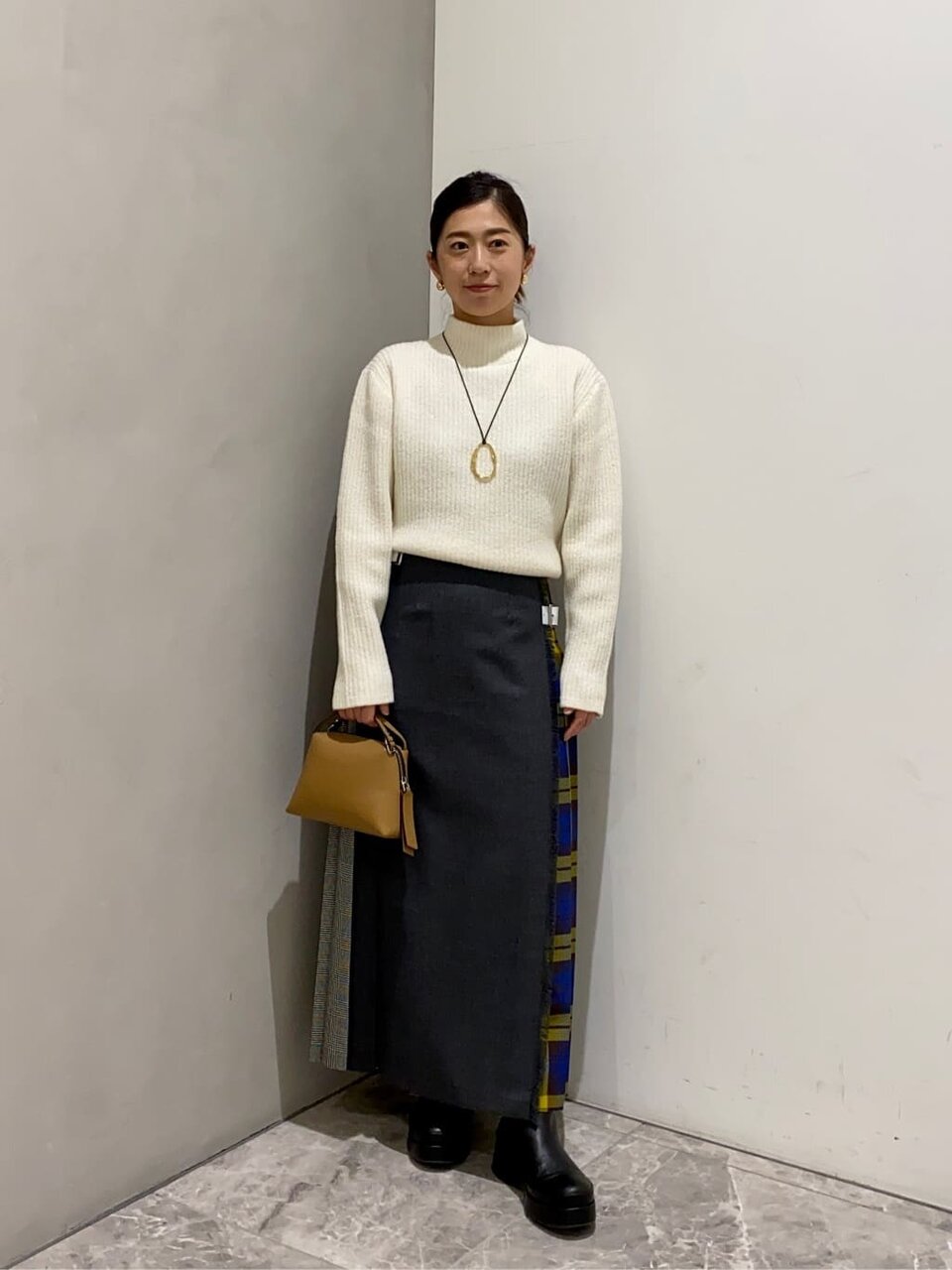 白いニットにパッチワークスカートを着た女性