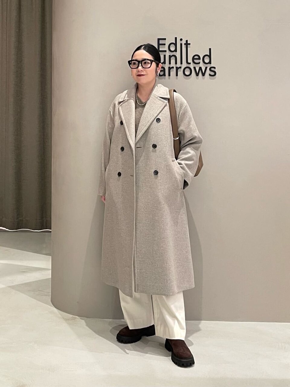 テーラードコートと白いパンツを着た女性