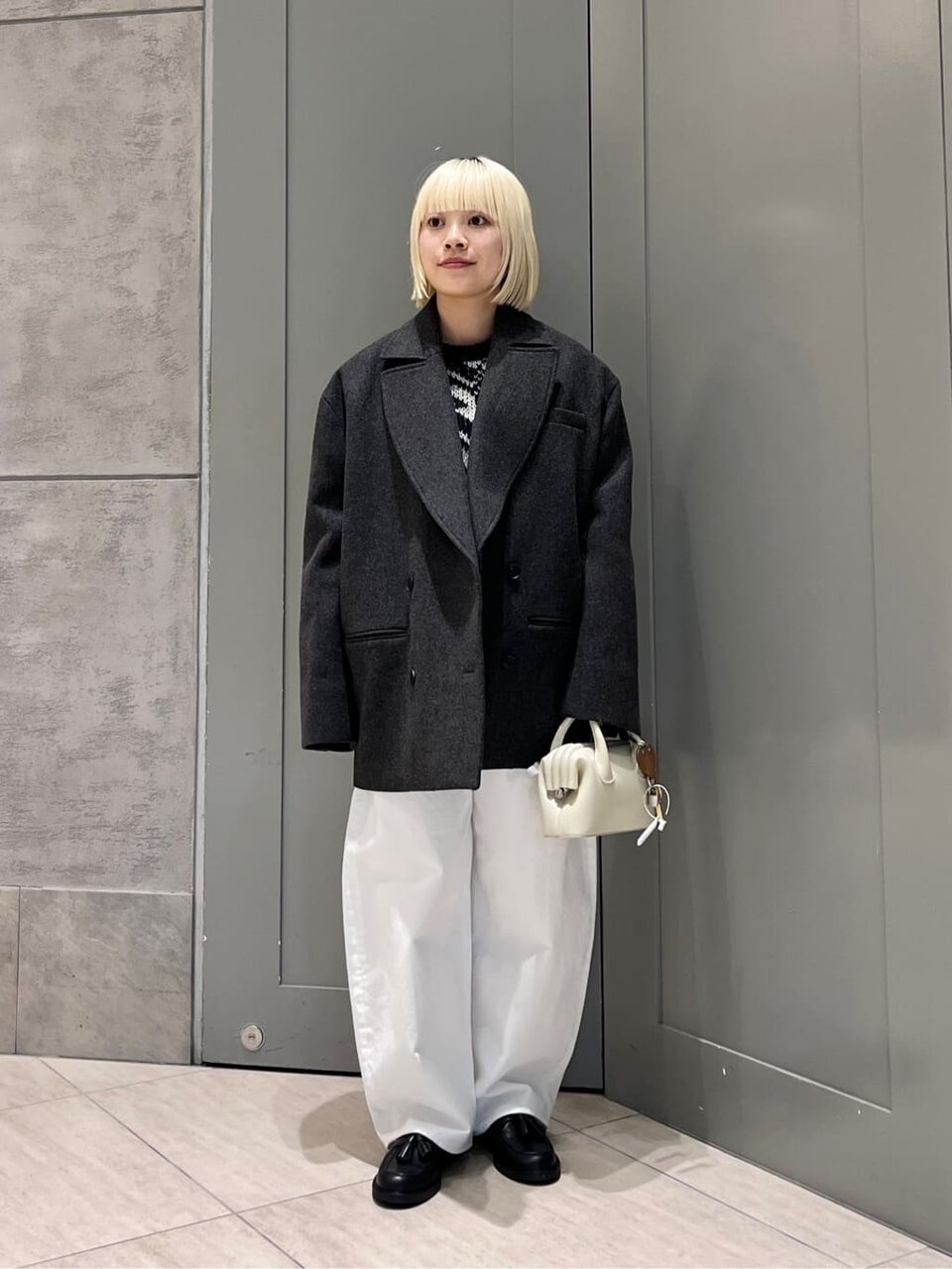 ハーフコートと白いパンツを着た女性