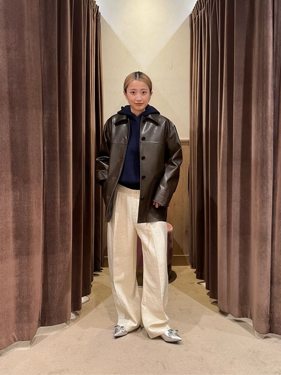 レザーブルゾンと白いパンツを着た女性