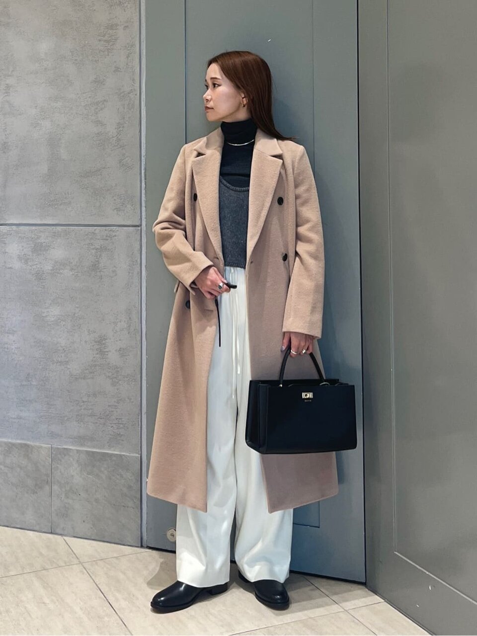 ロングコートと白いパンツを着た女性