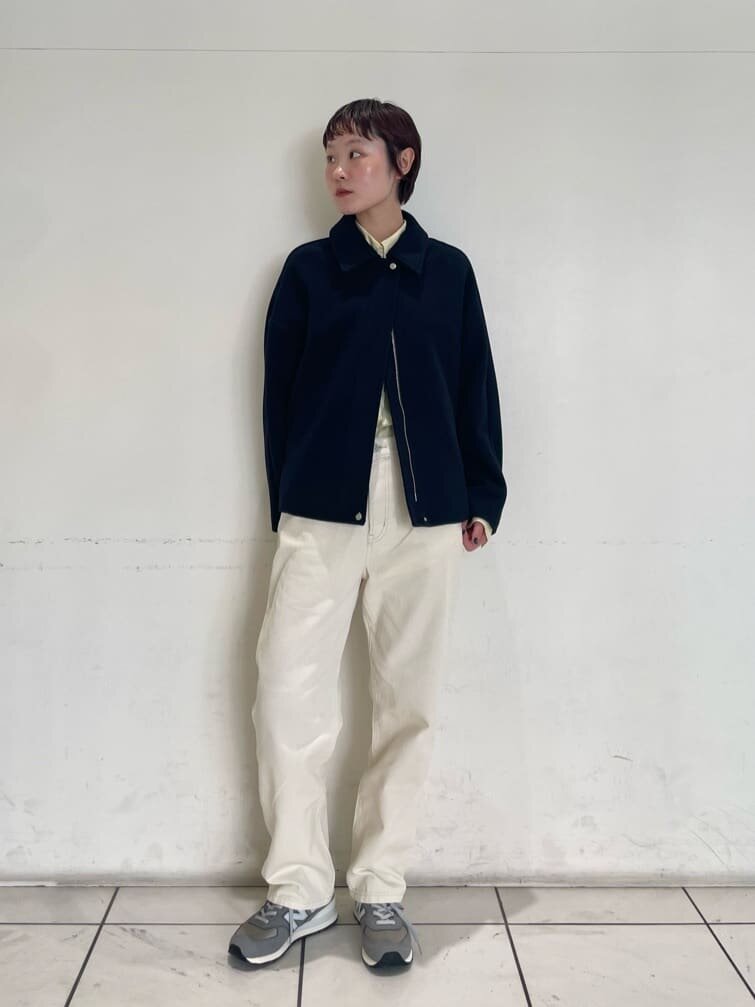 グレーのカーディガンと白いパンツを着た女性