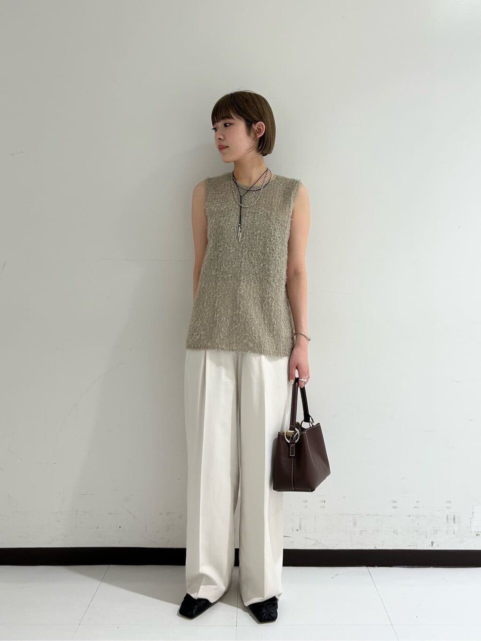 ノースリーブニットと白いパンツを着た女性