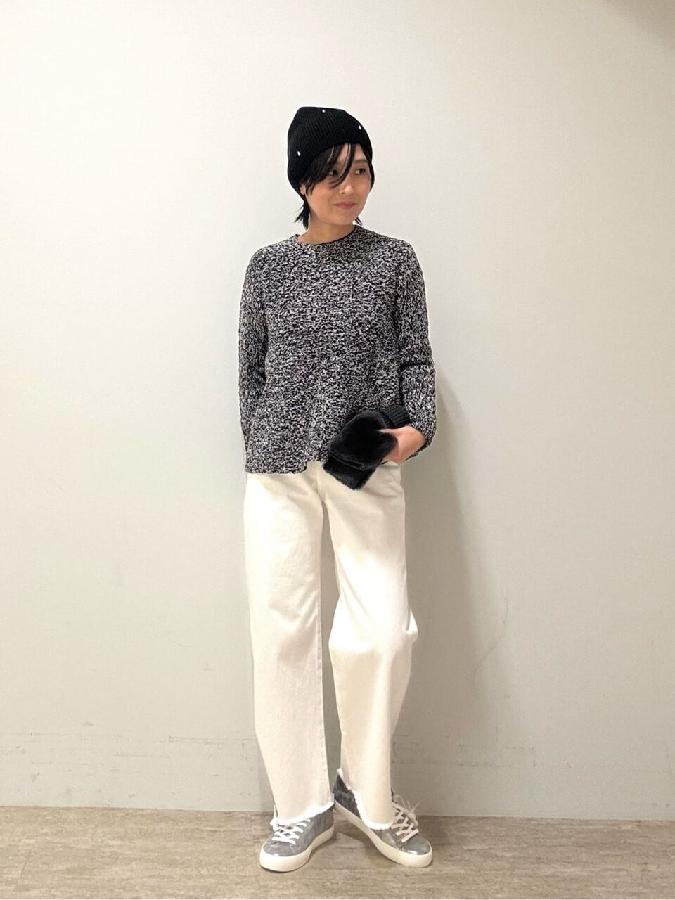 ペプラムニットと白いパンツを着た女性