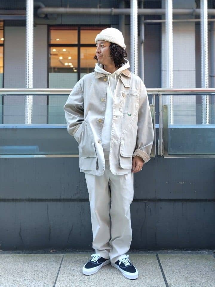 カバーオールと白パンツを着た男性