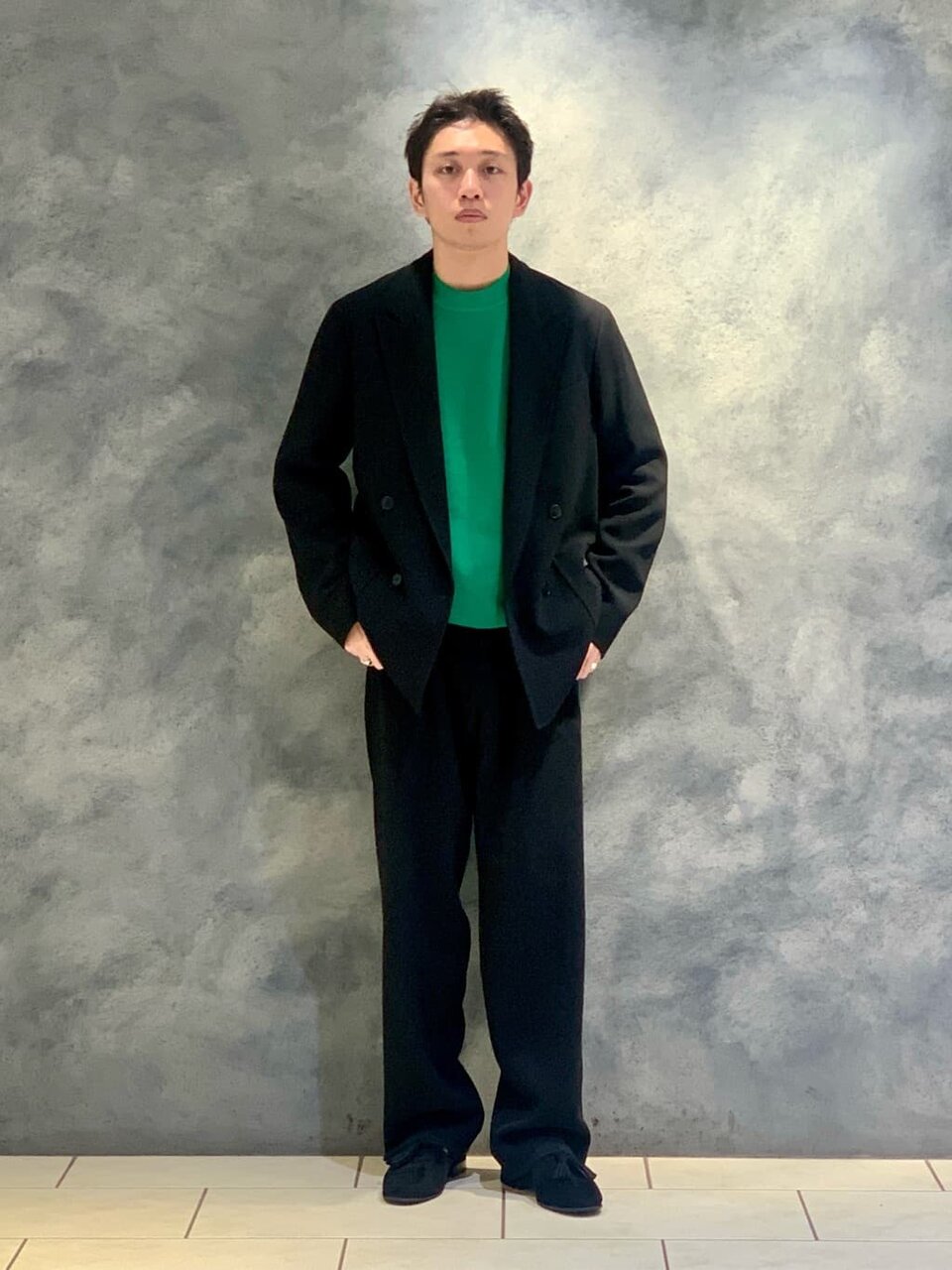 ケリーグリーンのクルーネックニットを着た男性