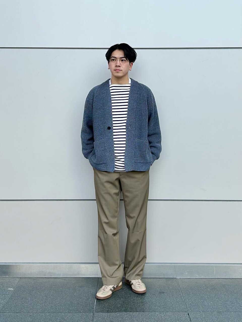 ニットカーディガンとスラックスを着た男性