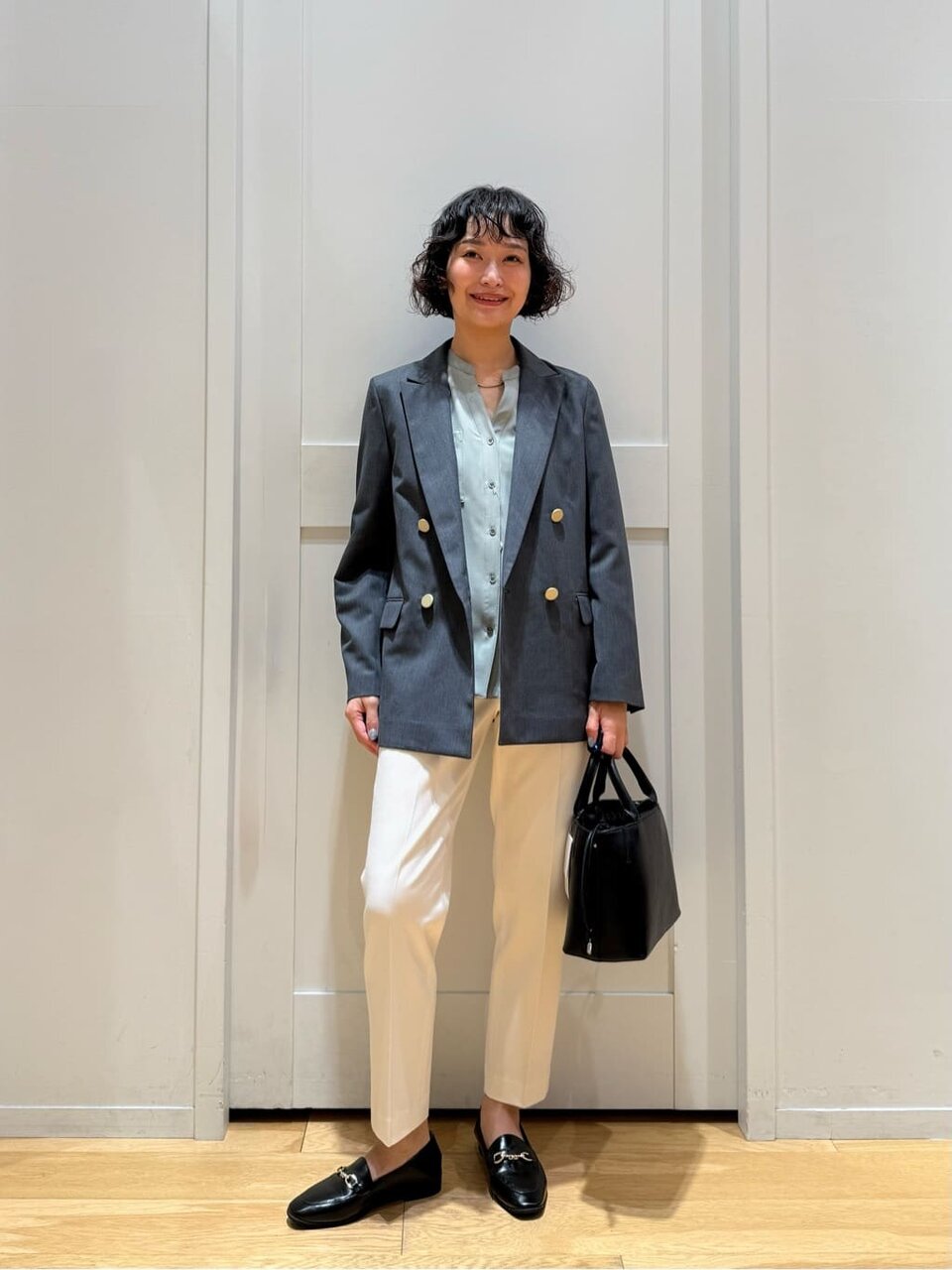 テーラードジャケットとローファーの女性