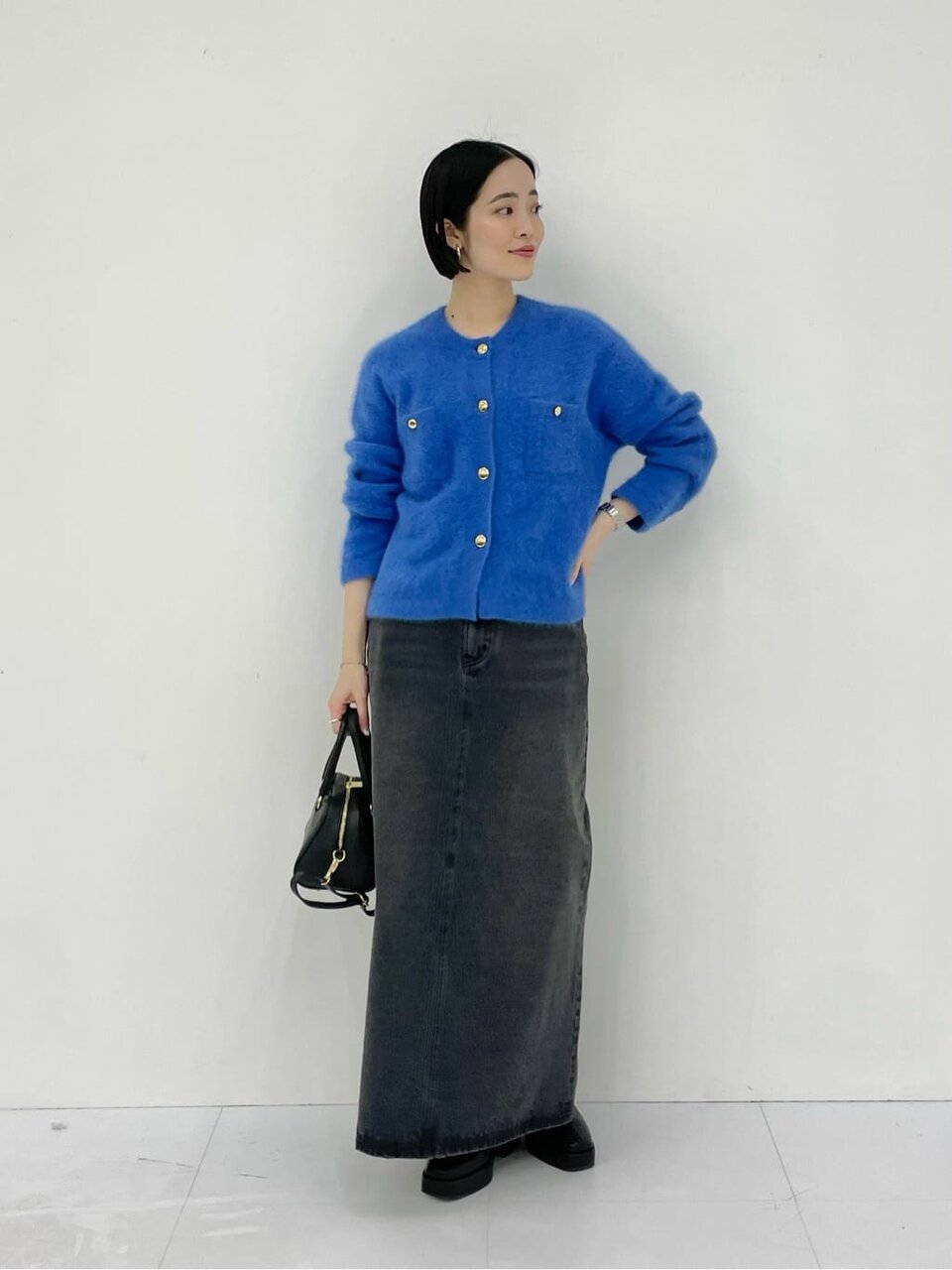 青いロングスカートと黒いトップスを着た女性