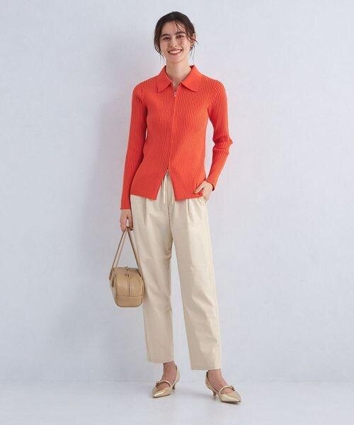 オレンジのニットとテーパードパンツを着用した女性