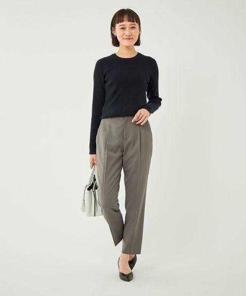 黒いニットとブラウンのテーパードパンツを着用した女性