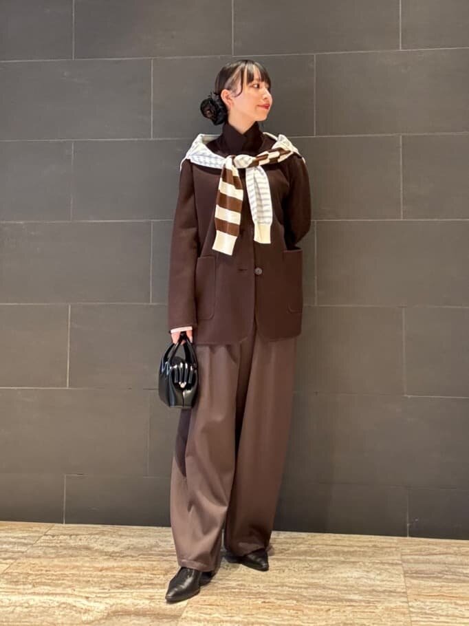ダークブラウンのパンツにコートをあわせた女性
