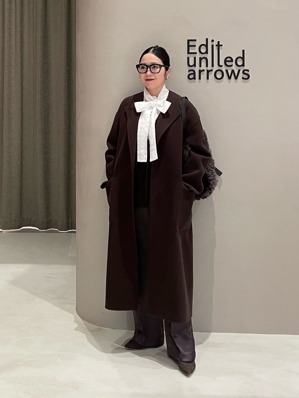 ダークブラウンのアウターにパンツをあわせた女性